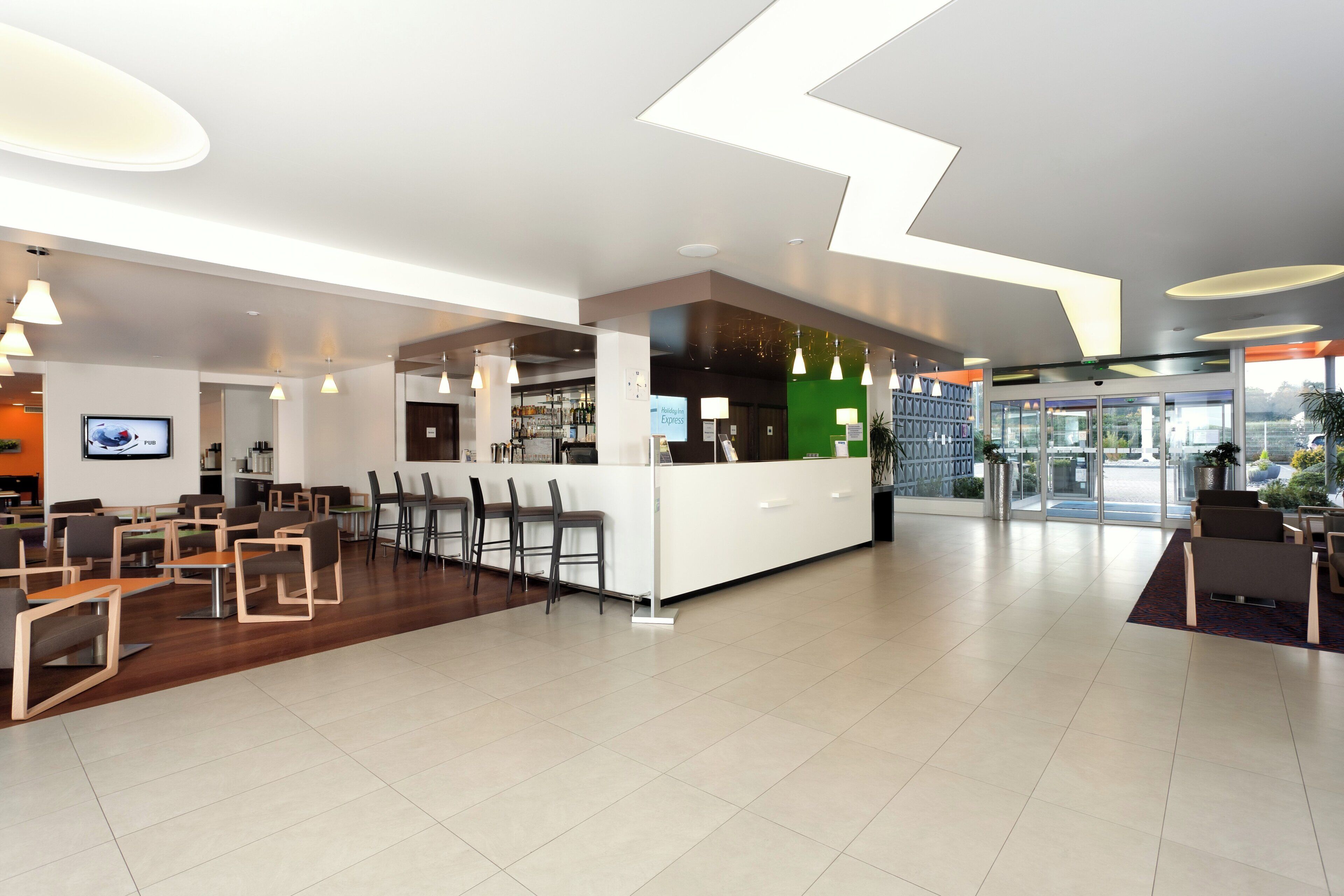 A modern hotel lobby with a bar area, seating arrangements, and a reception desk.