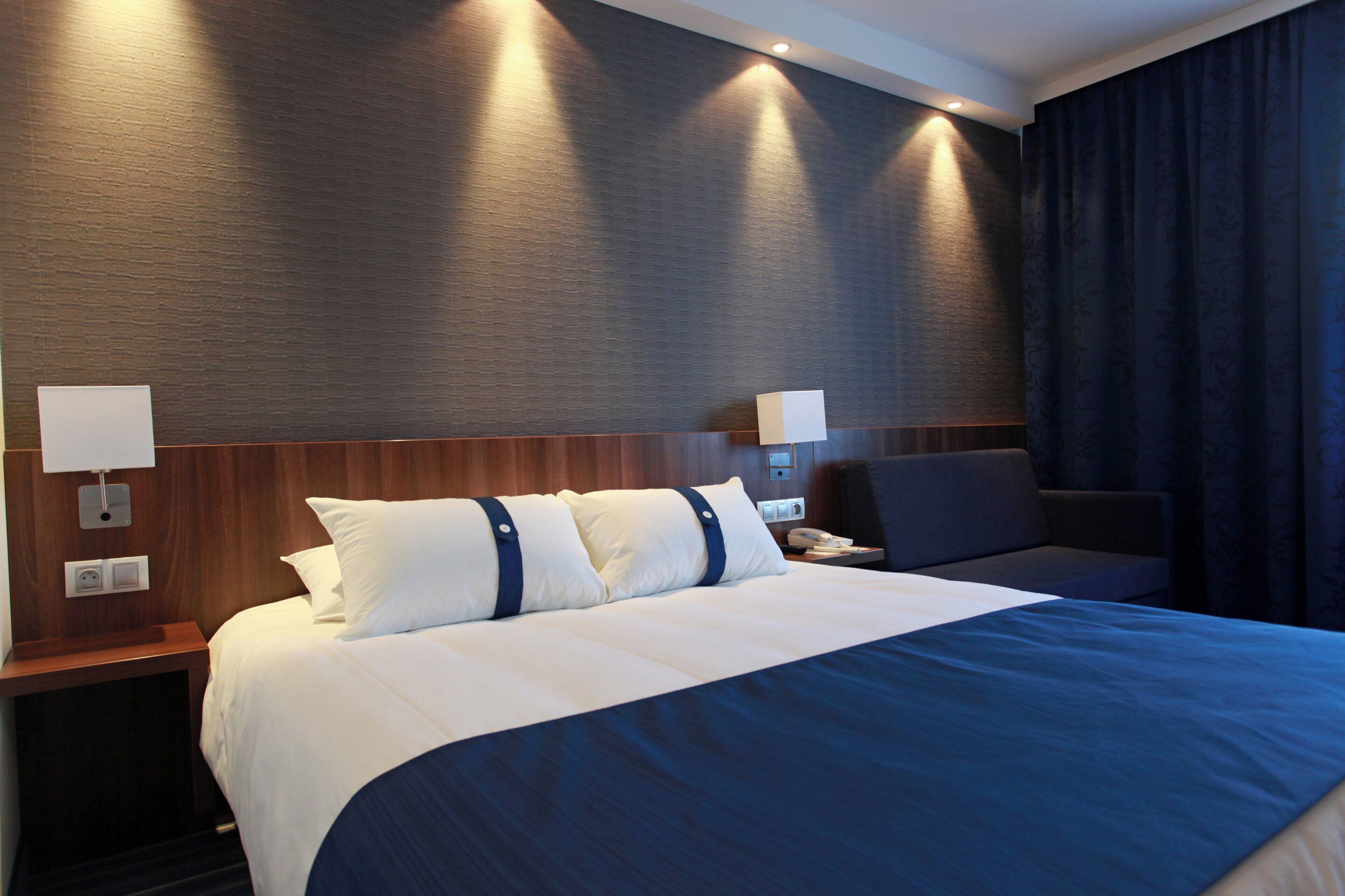 A hotel room with a large bed, two bedside tables, a nightstand, a desk, and a chair.