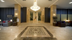 Eine geräumige Lobby mit einem großen Kronleuchter, Sitzbereichen und einem dekorativen Fußbodenmuster.