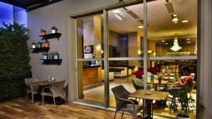 Ein modernes Interieur mit Holzboden, Korbmöbeln und einer Glastür, die in einen Essbereich führt.