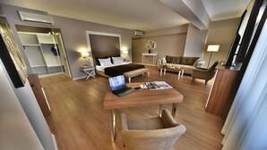 Ein modernes Hotelzimmer mit Bett, Schreibtisch, Laptop und einer Sitzecke.