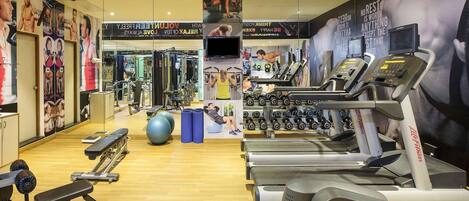 Un gimnasio con cintas de correr, máquinas de pesas y pelotas de ejercicio.