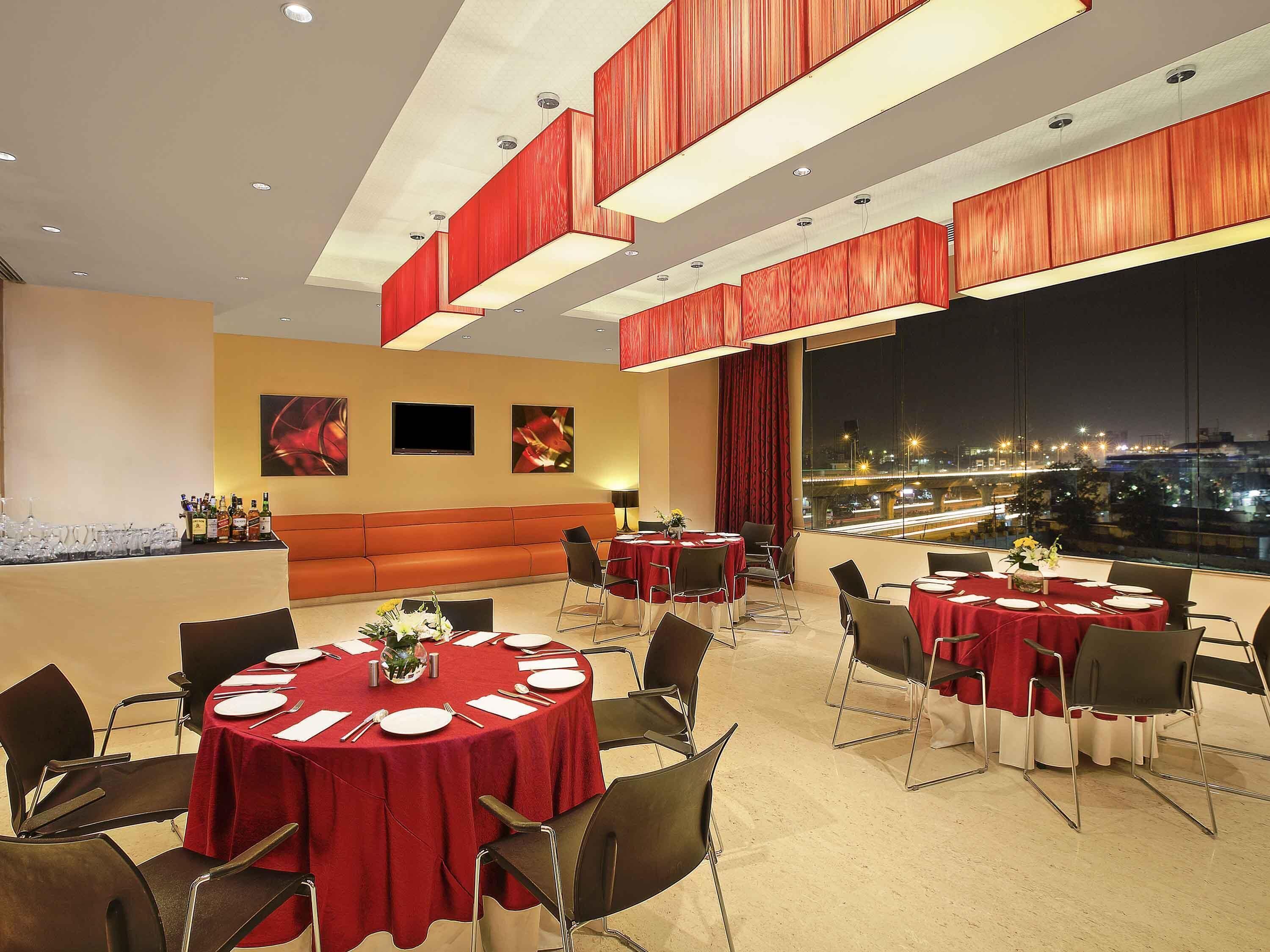 Un espace de restauration d'hôtel avec des tables rondes, un canapé et une vue sur la ville.
