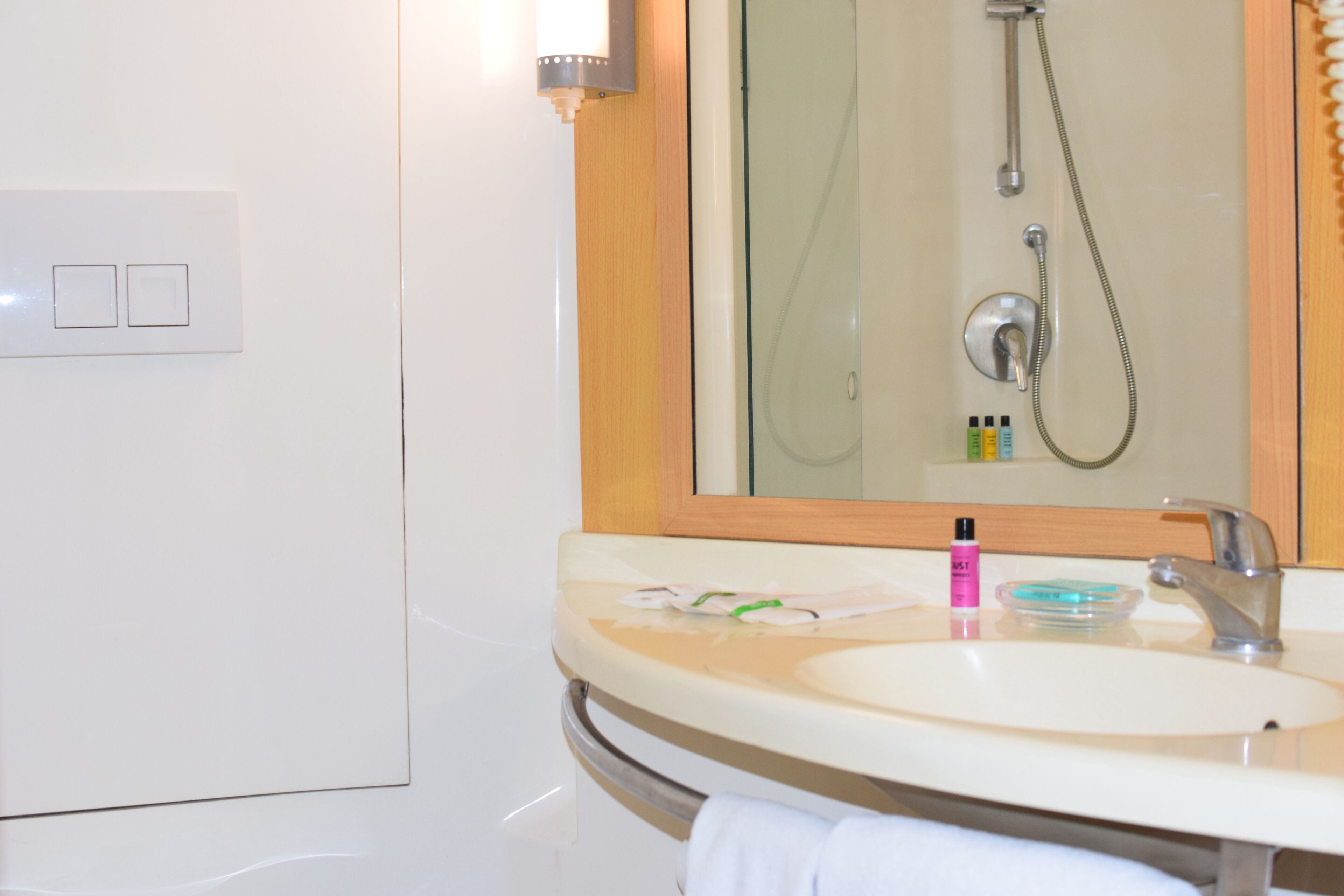 A bathroom with a sink, mirror, shower, and towel rack.