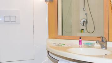 A bathroom with a sink, mirror, shower, and towel rack.
