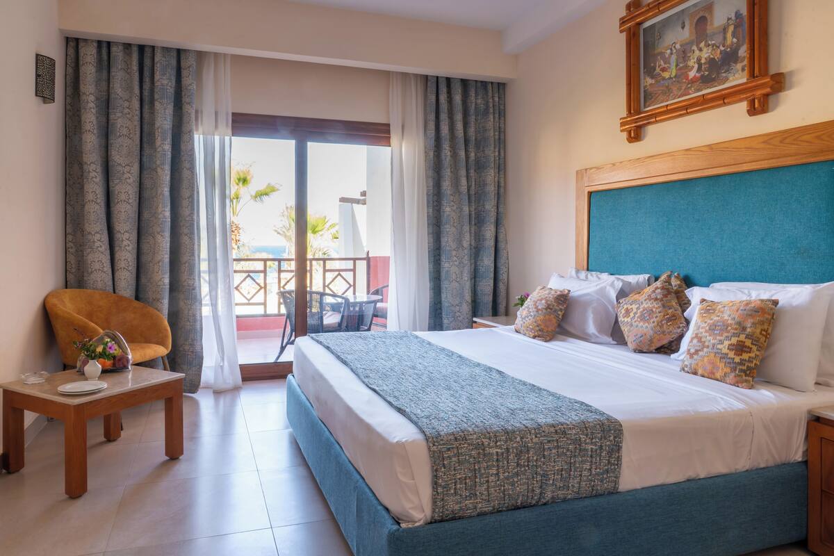 Una habitación de hotel con una cama, una mesita, una silla y vistas al exterior.