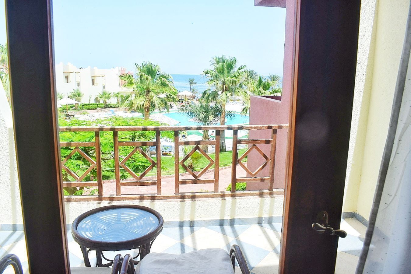 Ein Balkon mit Blick auf einen Pool und Palmen.