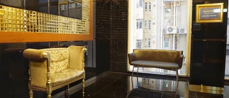 A lobby with a gold-framed chair and a cushioned bench.