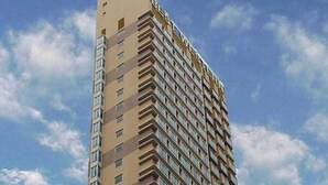 Un grand immeuble moderne, avec une façade beige et de nombreuses fenêtres.