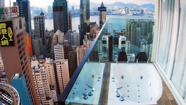Un immeuble de grande hauteur doté d’un balcon en verre qui offre une vue sur le paysage urbain.
