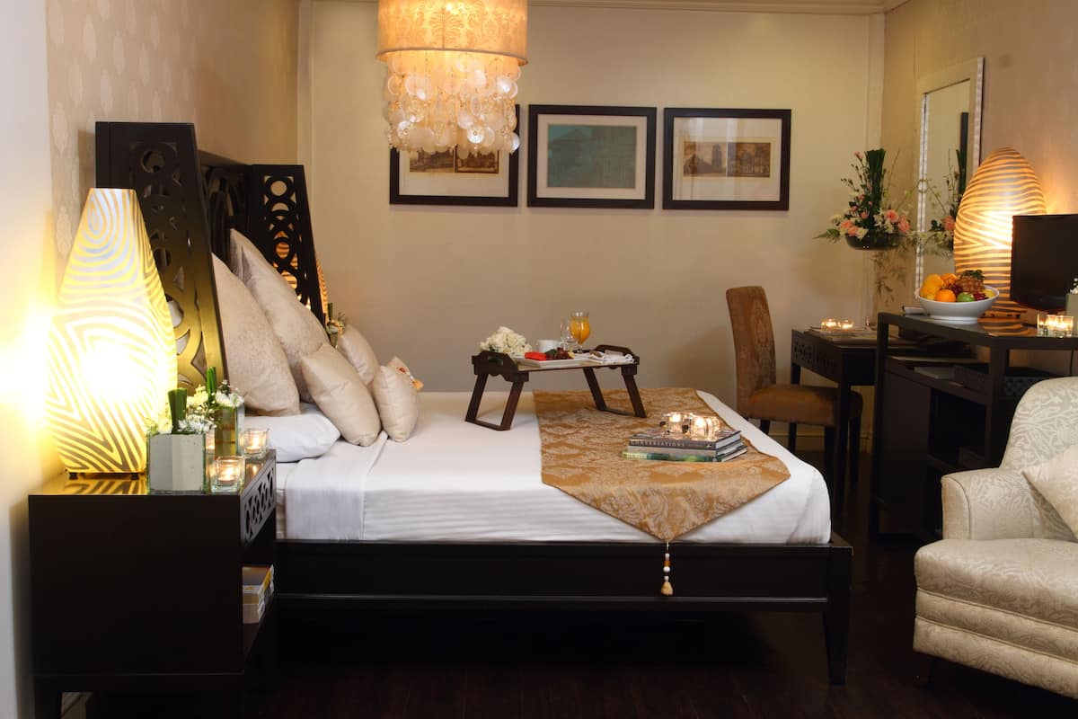 A well-lit bedroom with a bed, bedside tables, a desk, and a chair.