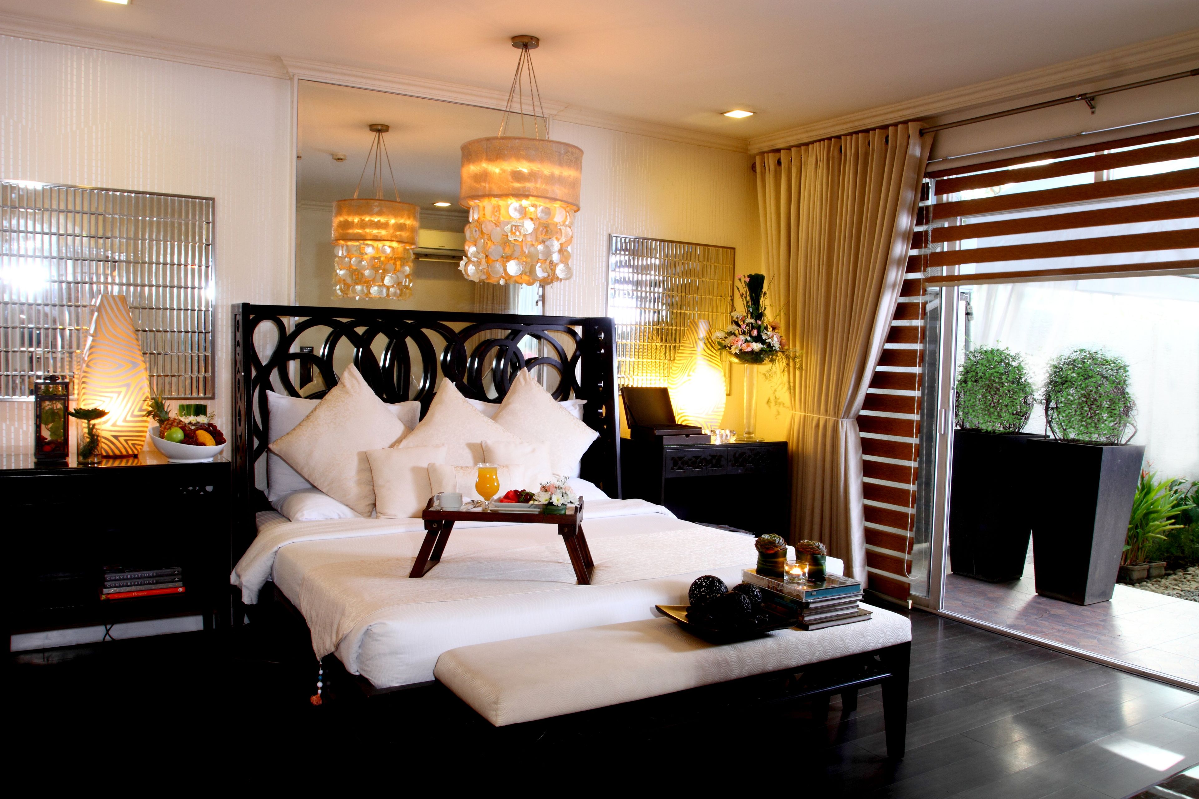 A modern bedroom with a large bed, bedside tables, a bedside lamp, and a view of the outdoors.