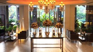 A spacious lobby with a central table adorned with floral arrangements, surrounded by seating. - Sulo Riviera Hotel (Quezon City)