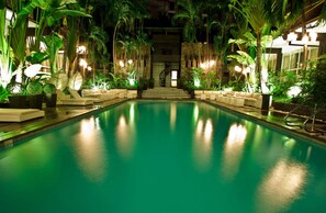 A pool area with a central staircase, surrounded by lush greenery and ambient lighting.