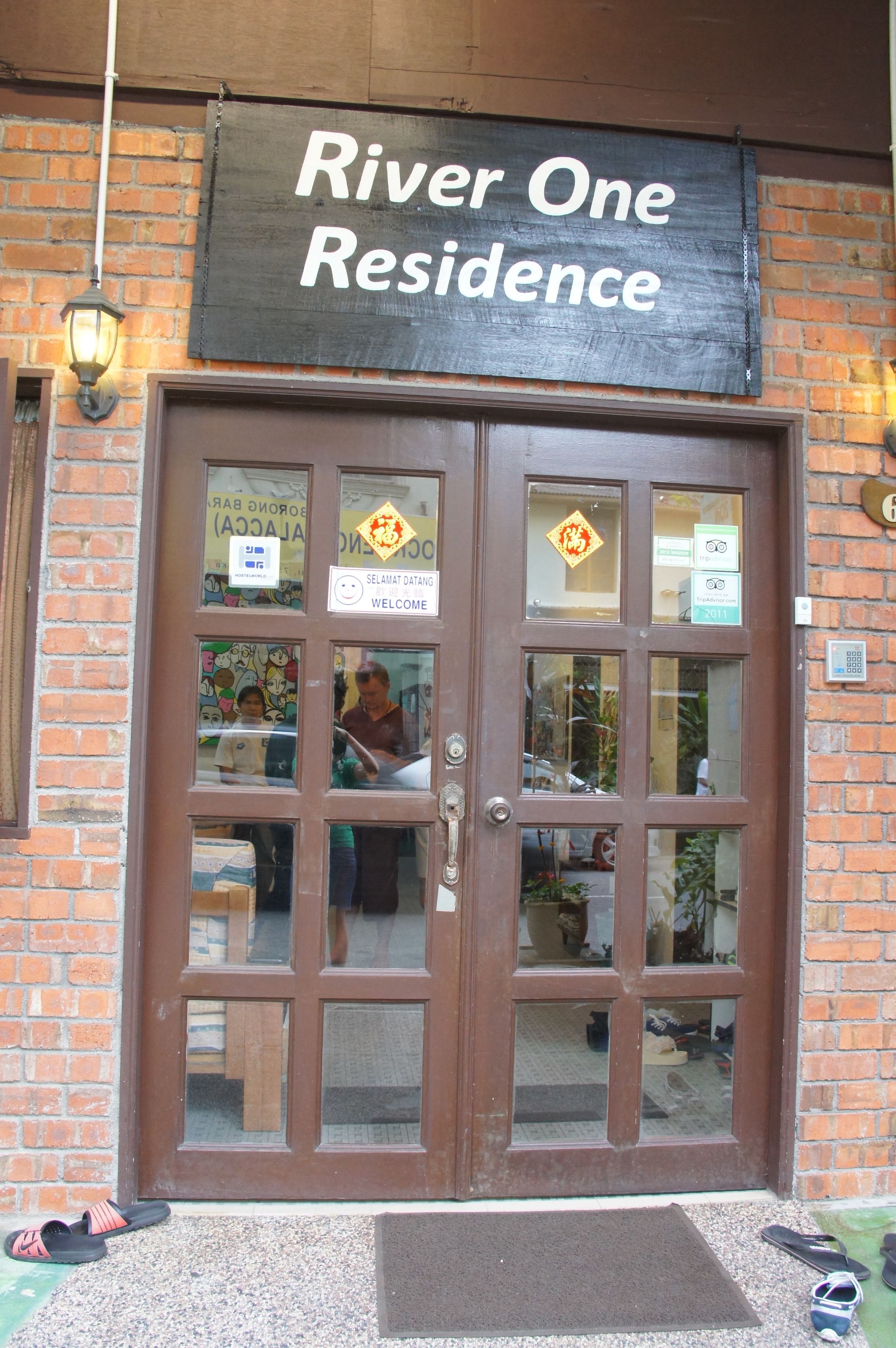 A brown double door with a sign above reading "River One Residence."