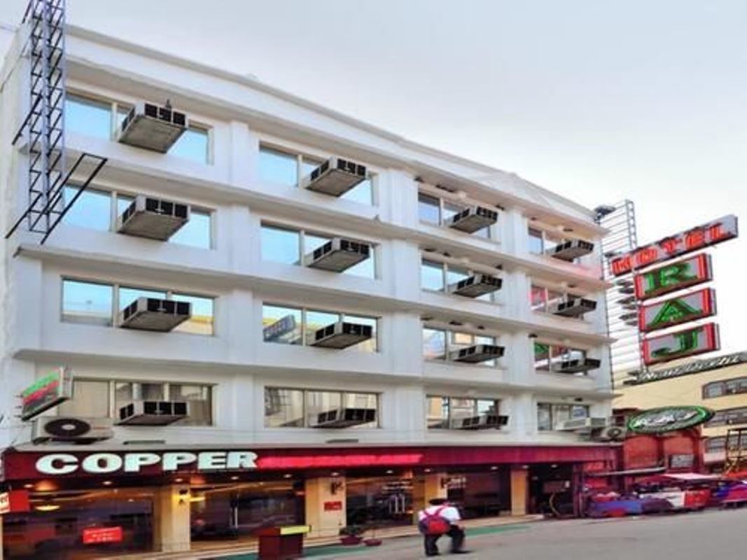 A multi-story building with a flat facade, multiple balconies, and a storefront with a red awning.