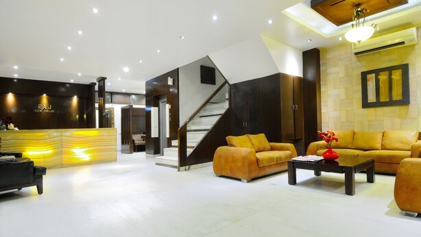 Un hall d’entrée moderne comprenant un comptoir d’accueil, un escalier et un espace détente avec des canapés et une table basse.
