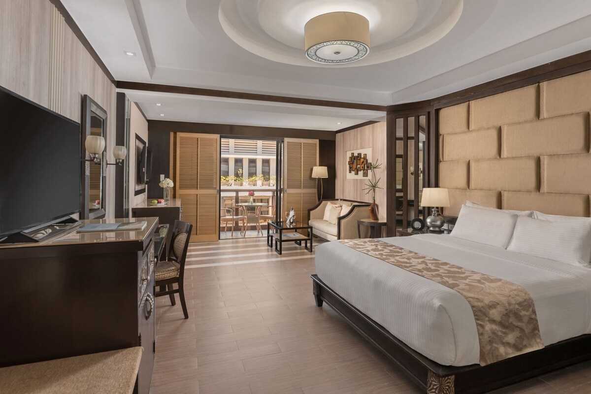 A hotel room with a bed, desk, television, and a view of the outdoors.