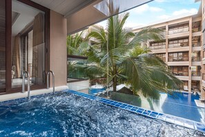A swimming pool with a glass barrier, palm trees, and a multi-story building in the background. - Henann Lagoon Resort (Boracay Island)