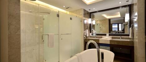 Un baño moderno con ducha envuelta en vidrio, una bañera independiente y un espejo grande sobre el lavamanos.