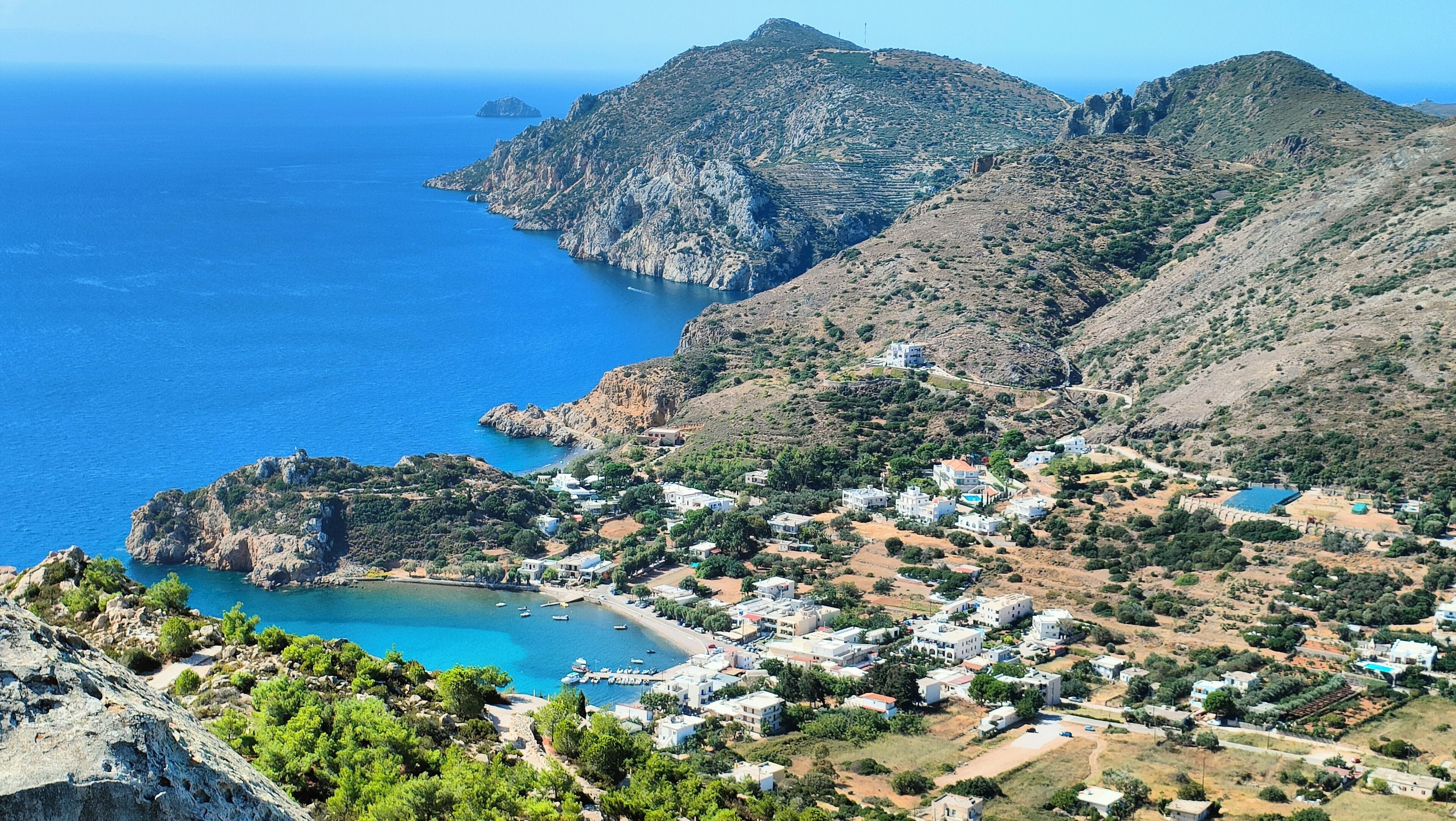 Un pueblo costero con edificios, una playa y montañas.