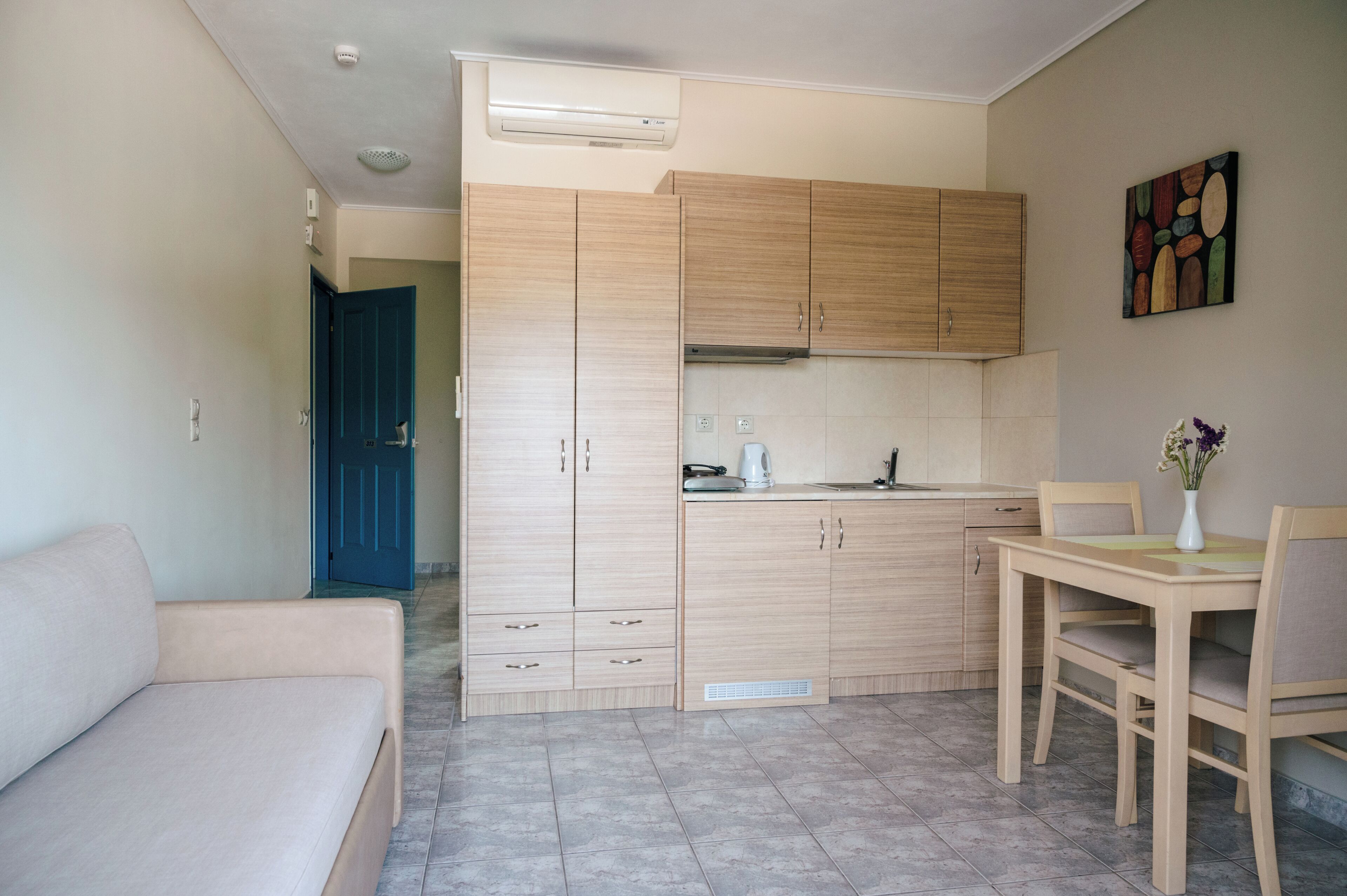 Un espacio habitable compacto con kitchenette, comedor y sofá.