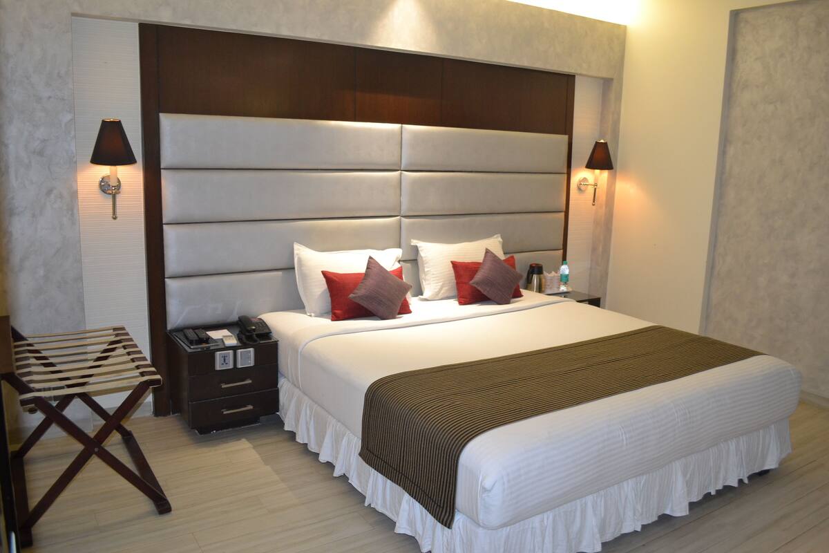 A hotel room with a large bed, two bedside tables, a desk, and a chair.