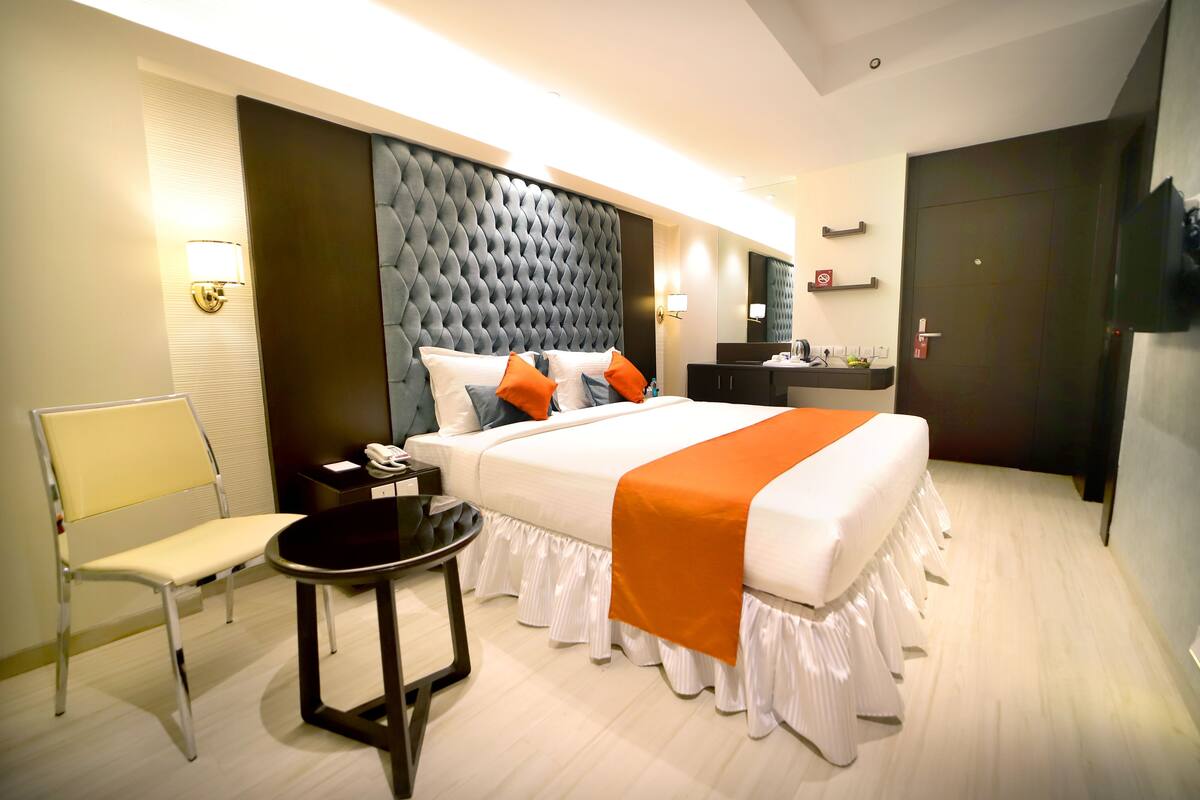 A hotel room with a large bed, a bedside table, a chair, and a small table.