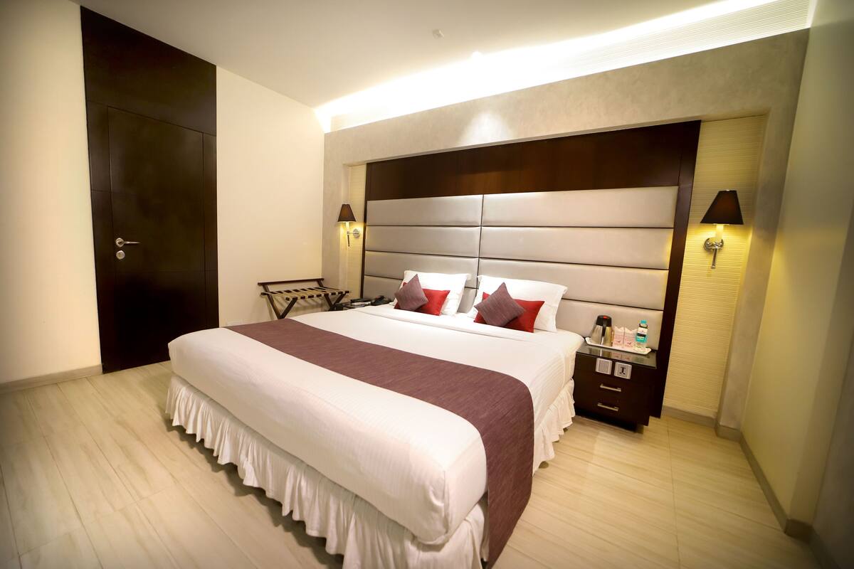 A hotel room with a large bed, a nightstand, a lamp, and a wardrobe.