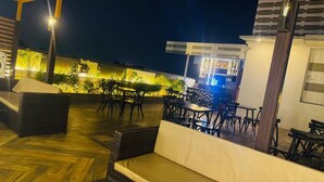 An outdoor seating area with wicker furniture and a bar with a blue-lit display. - Southern Plaza (Kolkata)