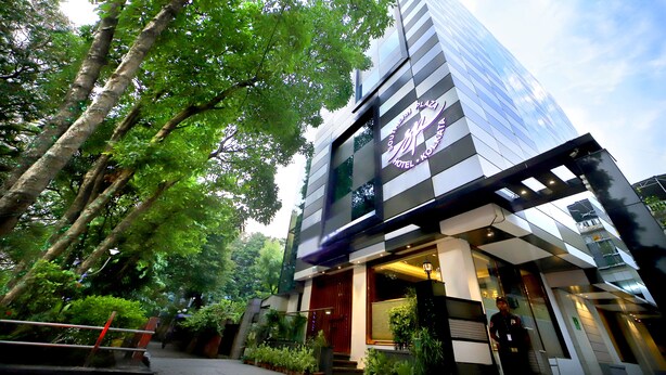 A modern hotel with a glass facade, surrounded by lush greenery. - Southern Plaza (Kolkata)