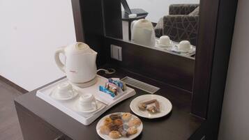 Une chambre d’hôtel équipée d’un coin café, d’un ordinateur portable posé sur une petite table et d’un lit recouvert d’une couverture à motifs.