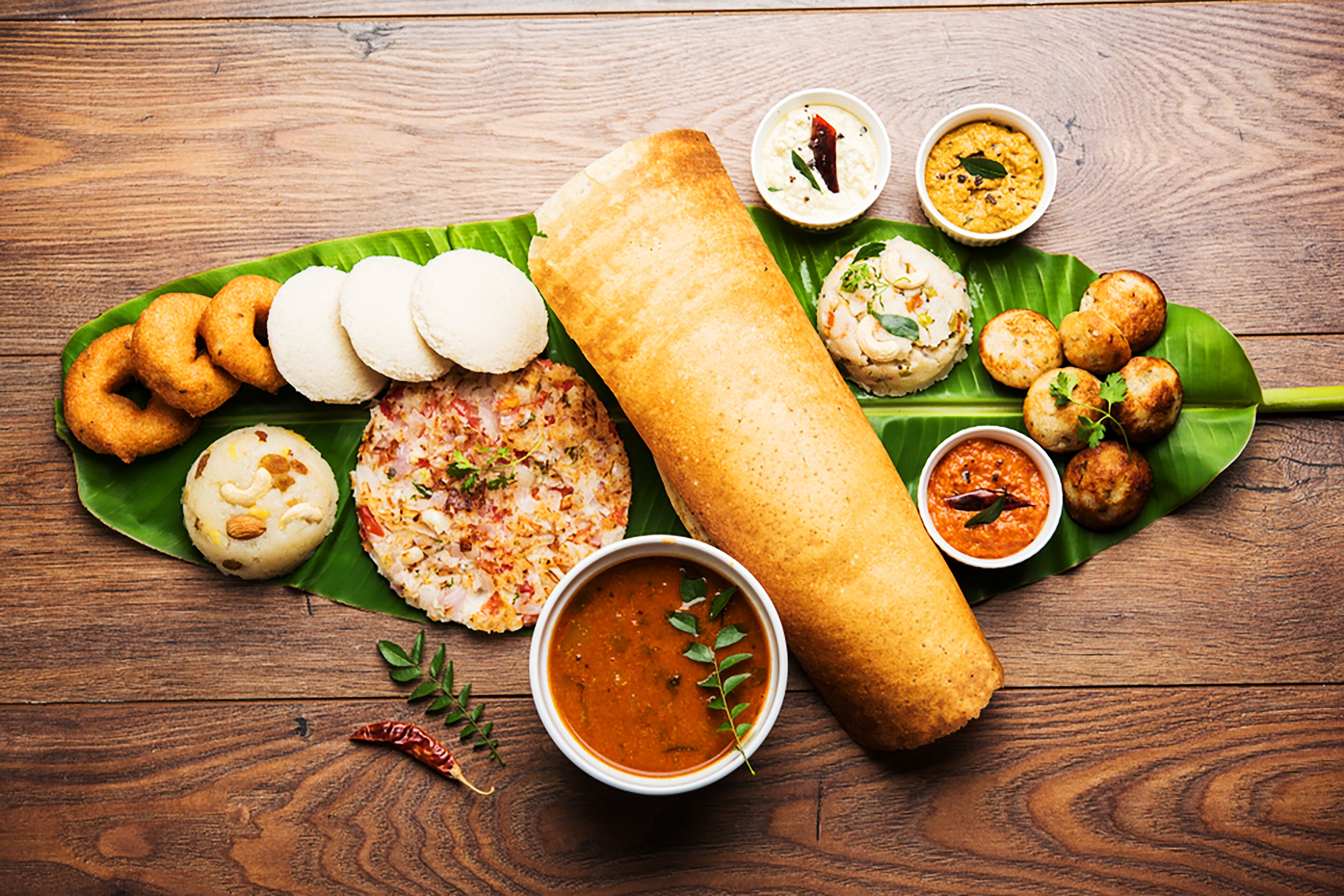 Diversos plats de l'Índia del Sud, com ara idlis, vadas i una dosa, presentats sobre una fulla de plàtan.