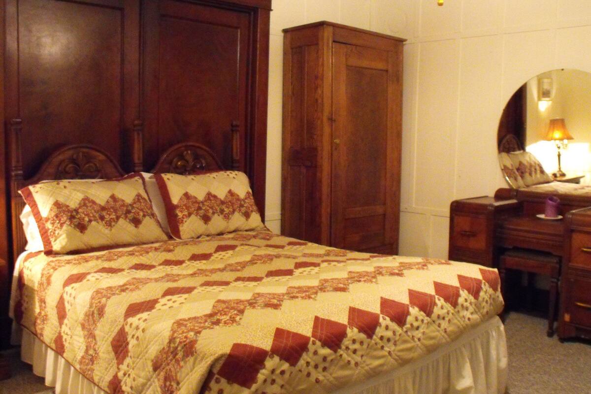 Ein Schlafzimmer mit einem großen Bett, einem Holzschrank und einem Nachttisch mit Lampe.
