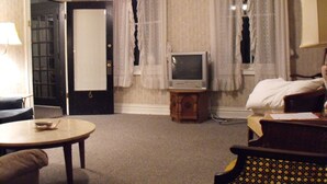 Une chambre d’hôtel avec un lit, un téléviseur posé sur un meuble en bois, une petite table et une chaise.