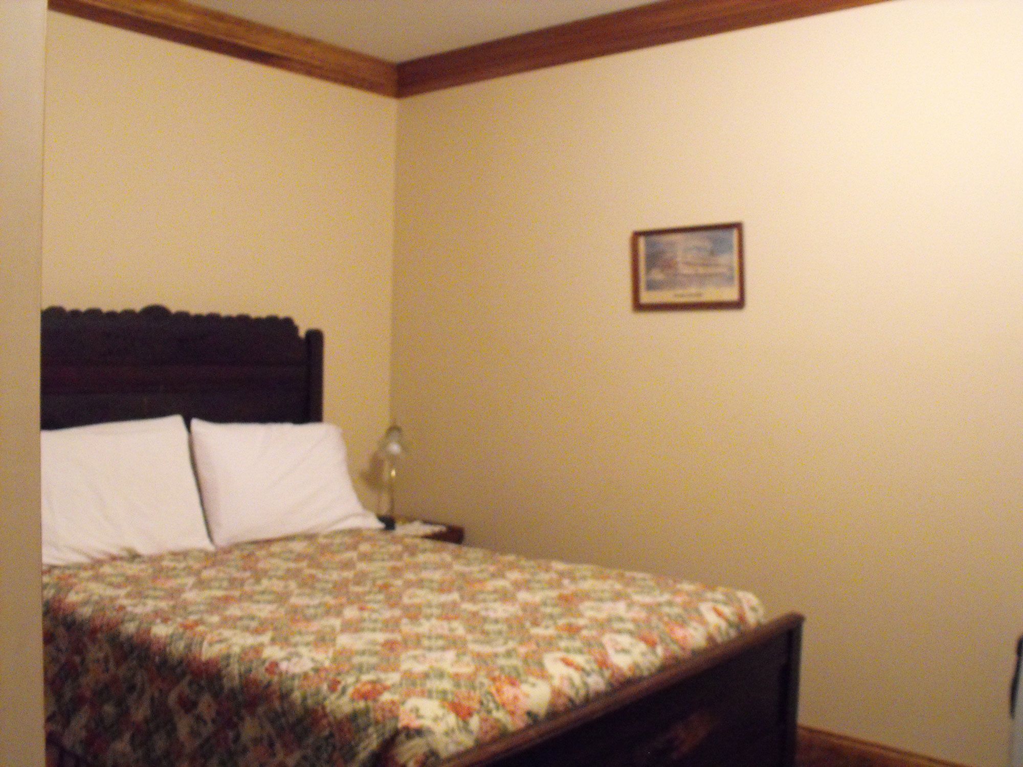 Un dormitorio con una cama, una mesita de noche y un cuadro en la pared.
