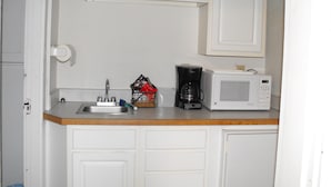 Une petite cuisine équipée d’un four à micro-ondes, d’une machine à café et d’un évier.