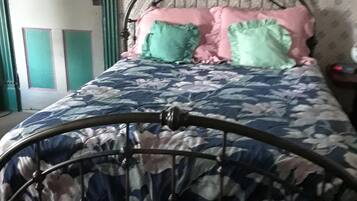 A bed with a metal frame, a floral-patterned bedspread, and a pink pillow.