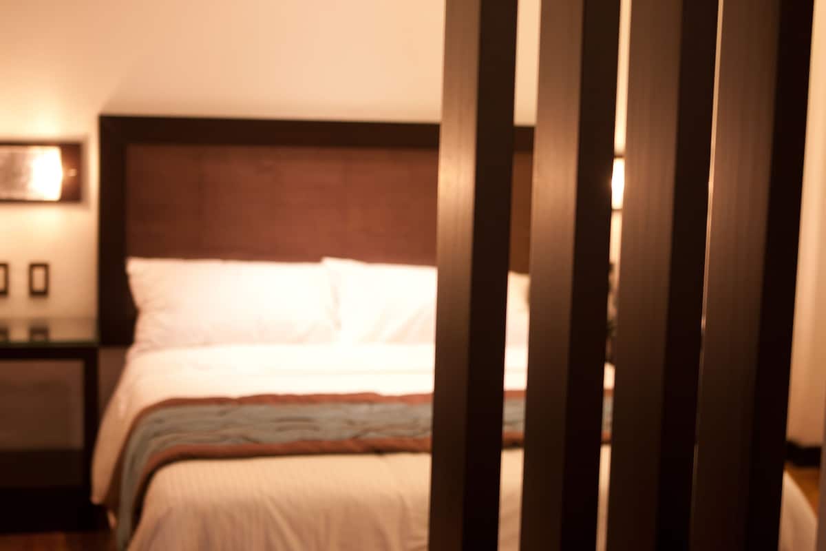A bedroom with a bed, wooden headboard, and bedside tables.