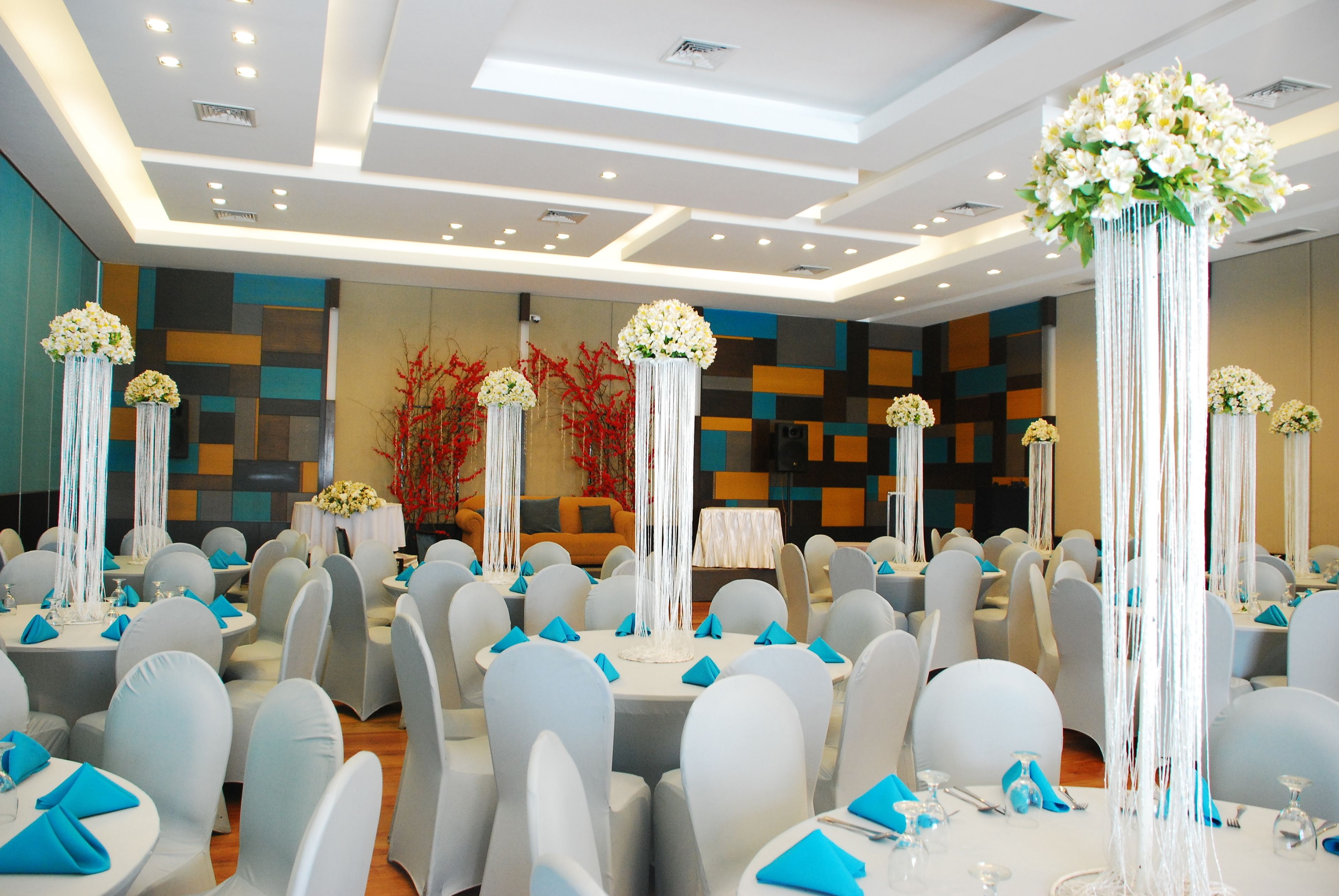 A banquet hall with round tables, white chairs, and blue napkins.