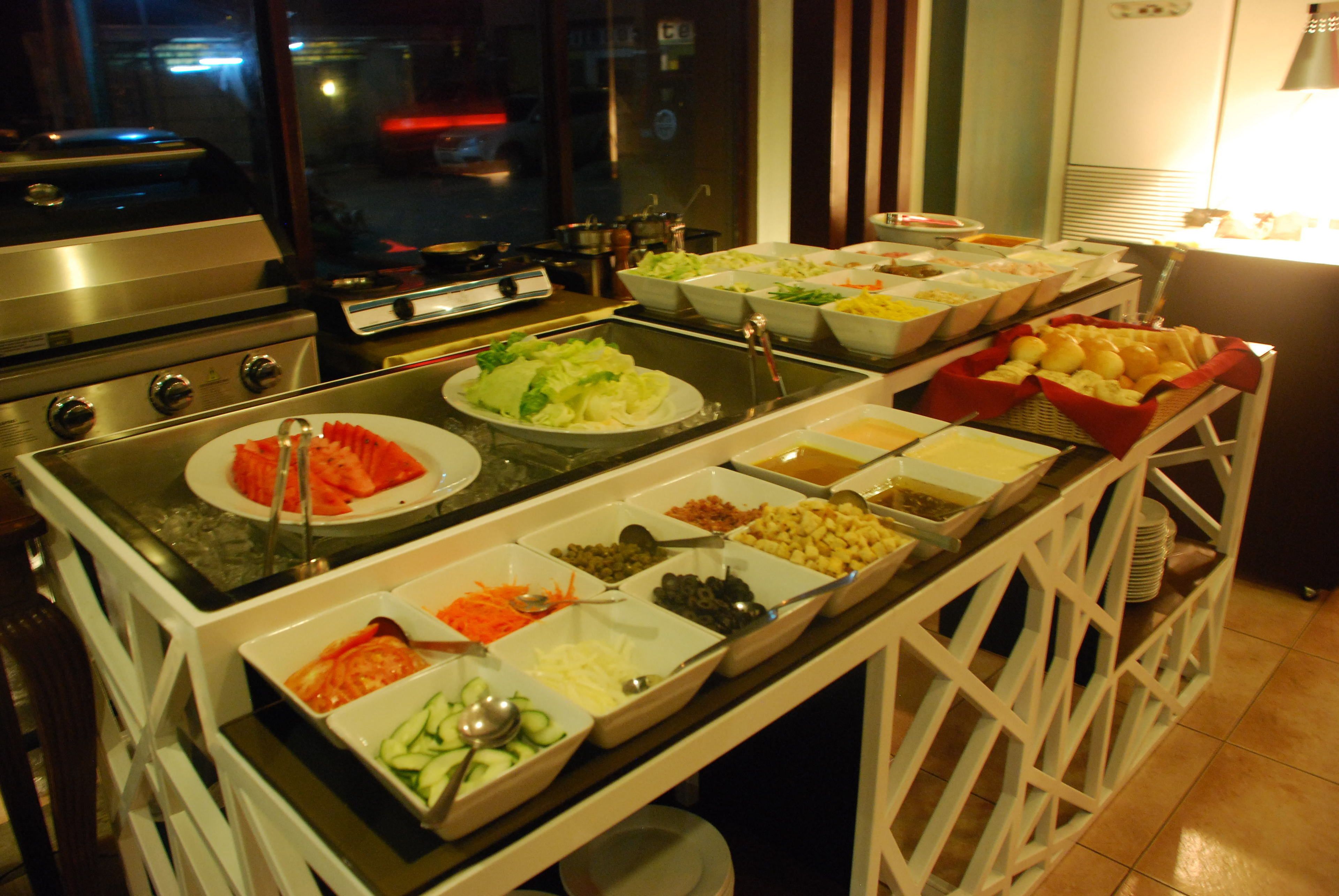 A buffet with various food items and a grill station.