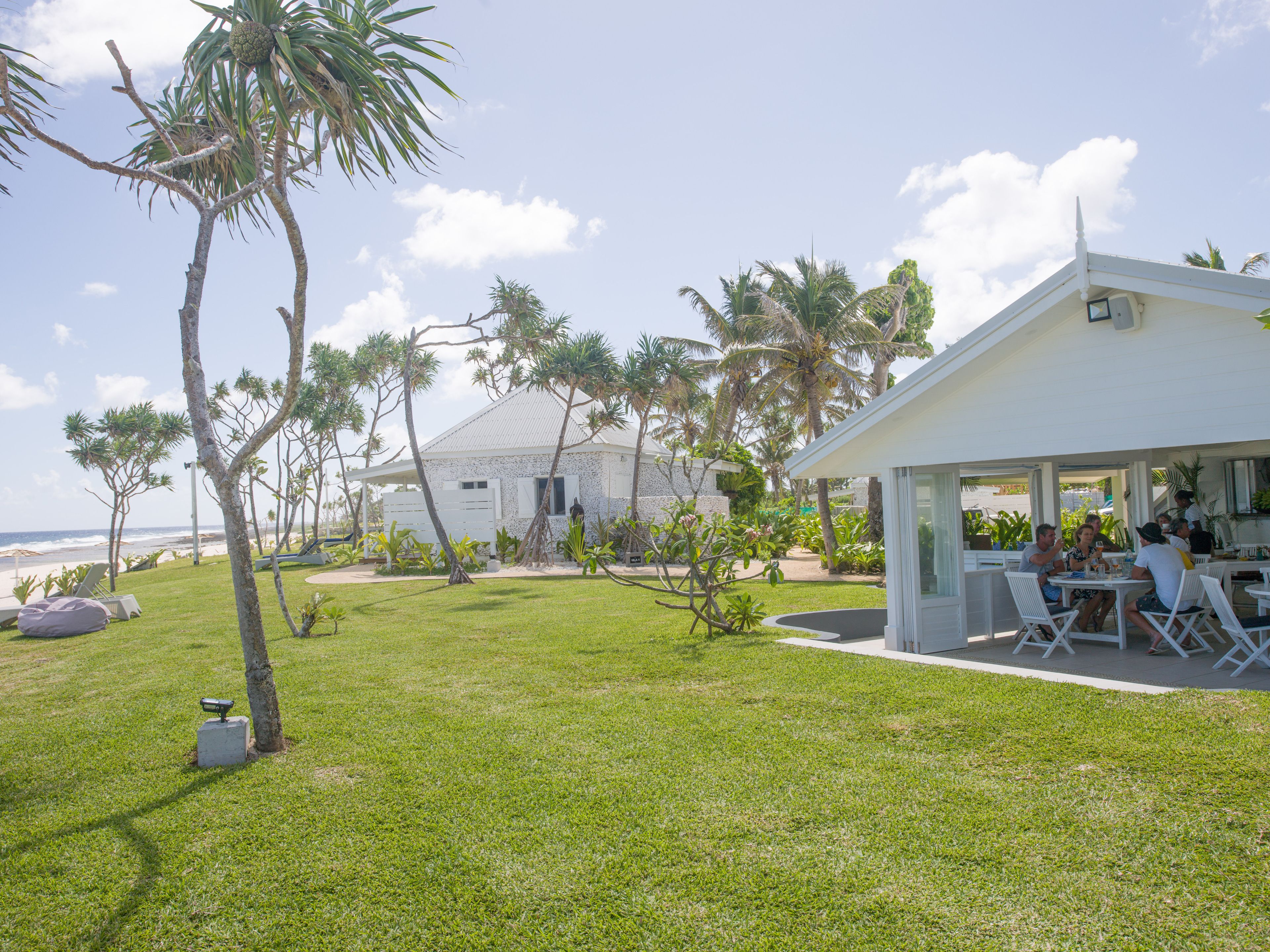 A white house with a covered patio and a lawn.