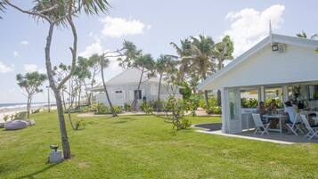 A white house with a covered patio and a lawn.