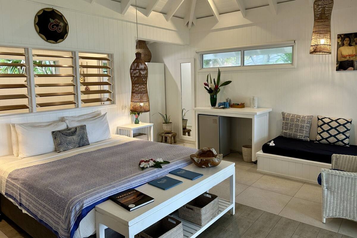 A spacious room with a large bed, a desk, and a seating area.