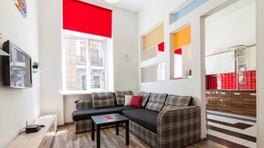 A modern living room with a sectional sofa, a small table, and a TV mounted on the wall. - Modern Properties Lviv (Lviv)