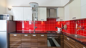 A modern kitchen with wooden cabinets, a built-in oven, a microwave, and a red-tiled backsplash. - Modern Properties Lviv (Lviv)