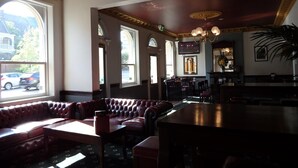 En restaurang med högt i tak, stora fönster och en bardisk.