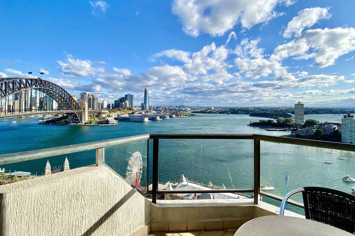 A balcony with a view of a city skyline, including a bridge and skyscrapers.
