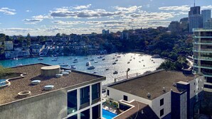 Ein modernes Gebäude mit Pool auf dem Dach und Blick auf einen Yachthafen mit Booten.