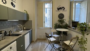 A compact kitchen with a washing machine, a sink, and a dining area with two chairs. - Colazione Al Vaticano (Rome)
